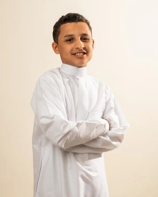 مفهوم الوسامة والاناقة، النظر إلى الكاميرا بإيماءات السعادة والسرور، صورة شخصية للوثائق الرسمية، الاهتمام بالمظهر الخارجي ، بورتريه لولد عربي خليجي سعودي يرتدي الثوب التقليدي يقف بأيدي متقاطعة ، خلفية بيضاء