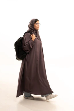 Gestures of walking and heading to school, perseverance to achieve excellence and success, a side portrait of an Arab Gulf Saudi student wearing a hijab and abaya carrying a school backpack, ready to start the new school year with expressions of joy, full body length, white background.