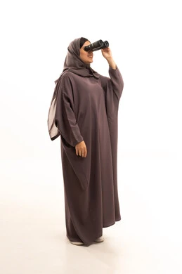 حب الاستكشاف والمغامرة، التخطيط المستقبلي للأهداف و الطموحات، بوتريه امرأة عربية سعودية خليجية محجبة تمسك بيدها منظار ثنائي العينين ( التلسكوب ), الرؤية بالعدسة المكبرة , ايماءات وجه تدل السعادة و السرور , الجسم بالطول الكامل، خلفية بيضاء