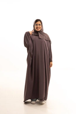 الاشارة إلى شيء ما، تحديد موقع شيء معين,إشارات وحركات يدين تدل على هذا المكان (هنا)، بورتريه لامرأة عربية خليجية سعودية محجبة ترتدي عباءة تشير بإصبع السبابة إلى وجهها، الجسم بالطول الكامل, خلفية بيضاء