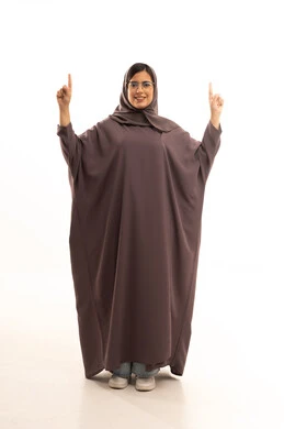 تعابير تحدد هذا المكان هنا،بورتريه لامراة عربية خليجية سعودية محجبة ترتدي العباءة و الحجاب و نظارة طبية  تشيربإصبع السبابة لاعلى إلى شيء ، النظر إلى الكاميرا بإيماءات الفرح والسرور، تحديد موقع معين، الجسم بالطول الكامل، خلفية بيضاء