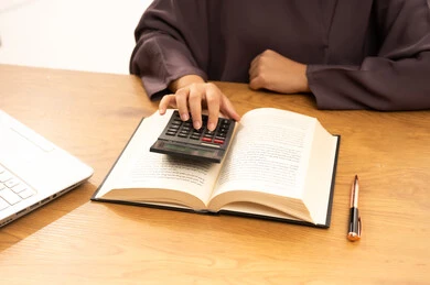 استخدام الآلة الحاسبة لإجراء العمليات الحسابية, بورتريه مقرب ليد شابه عربية خليجية سعودية تقوم بتحضير المشاريع الجامعية , أهمية التعليم في بناء مستقبل مشرق للمجتمع السعودي ,إيماءات الإجتهاد والاهتمام بالعلم والتعلم , خلفية بيضاء