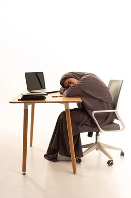 Fatigue and stress during studying, the importance of rest and good sleep in enhancing the mental and physical health of students, a portrait of a Saudi Arabian Gulf student wearing an abaya taking a nap while studying her lessons, studying late at night, black background.