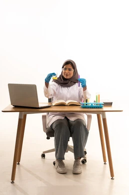 Conducting chemical experiments and applying research development methods, acquiring knowledge and experience with gestures of precision and focus, studies and experiments in an advanced practical environment, a portrait of a Saudi Gulf Arab student wearing a white coat and protective glasses holding a test tube in her hand sitting in front of a laptop conducting a scientific experiment, white background.