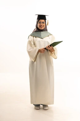 Looking at the camera with gestures of happiness, education in the Kingdom of Saudi Arabia, celebrating the completion of university studies, a portrait of a smiling veiled Arab Gulf Saudi graduate wearing an abaya and cap holding her graduation certificate in her hand, full-body length, white background.
