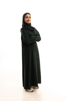 Looking at the camera with gestures of joy and self-confidence, the concept of elegance and attention to appearance, a portrait of a Gulf Arab Saudi woman wearing a hijab and traditional abaya standing with crossed arms, full-body image, white background.