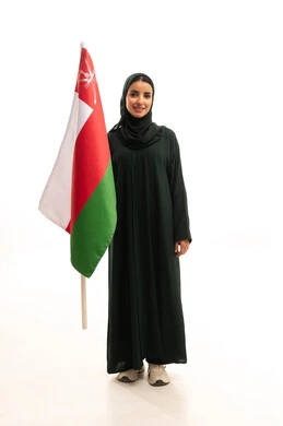 Cultures and national symbols, commemorating the founding of the state in 1775 AD, love for the homeland and belonging to it, a portrait of an Arab Gulf Omani woman wearing a hijab and abaya holding the national flag of the country celebrating the anniversary of Omani National Day on November 18, full-body, white background.