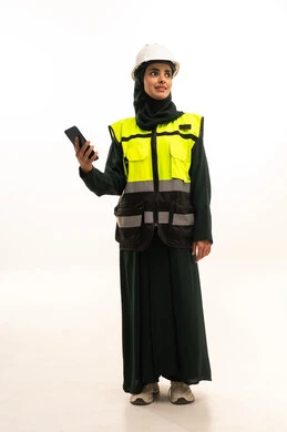 Looking at something, working in the engineering sector, a portrait of an Arab Gulf Saudi engineer wearing an abaya, helmet, and protective vest, monitoring the progress of work remotely via a mobile phone, integrating advanced technology with engineering, modern technical devices, full-body, white background.