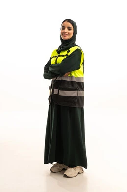 Engineering project management, jobs and professions for women, a portrait of an Arab Gulf Saudi female architect wearing an abaya and a safety vest standing with crossed arms, working in the engineering sector, full-body image, white background.
