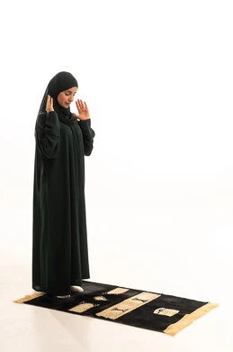 مفهوم أركان الإسلام، أداء الفرائض بأوقاتها،  الدعاء و التضرع لرب العباد، العبادة والتقرب إلى الله، الركوع والسجود والخشوع، بورتريه لشابة عربية خليجية سعودية مسلمة ترتدي الحجاب و العباءة  السوداء تقف على السجادة ، صورة الجسم بالطول الكامل، خلفية بيضاء