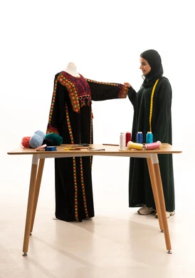 بورتريه لامراة عربية خليجية سعودية ترتدي الحجاب و العباءة السوداء تعمل على أخذ القياسات، مصممة أزياء مبتكرة، ورشة عمل تصميم ازياء، أدوات الخياطة، مهن وأعمال فن الخياطة، فنون ومهارات تصميم وتفصيل الملابس النسائية ، مفهوم عالم الأزياء والموضة، خلفية بيضاء