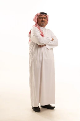 Standing with arms crossed, aging and dignity, a portrait of an elderly Arab Gulf Saudi man wearing traditional thobe and shemagh standing upright, attention to elegance and appearance, expressions of dignity and respect, the concept of Arab masculinity, full-body, white background.
