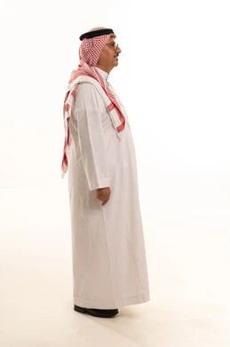 Expressions of dignity and respect, aging and stature, a side portrait of an elderly Arab Gulf Saudi man wearing traditional attire and a headscarf standing upright, attention to elegance and appearance, the concept of Arab masculinity, full-length body, white background.