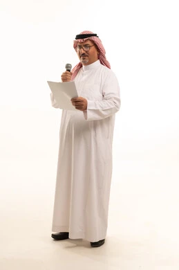 مهارة وفن الألقاء، تقديم فقرات ترفيهية، مواهب غنائية، التقدم بالعمر والهيبة، بورتريه  لرجل كبير بالسن عربي خليجي سعودي يرتدي الثوب التقليدي و الشماغ يقف باستقامة و يحمل بيده الميكروفون،,  مفهوم الرجولة العربية, الجسم بالطول الكامل، خلفية بيضاء