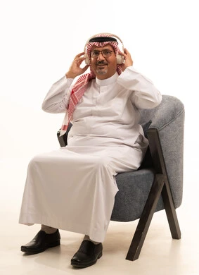 The concept of listening and paying attention to something, spending enjoyable and entertaining times, listening and enjoying using headphones, listening to artistic singing talents, a portrait of an elderly Arab Gulf Saudi man wearing traditional attire and a headscarf, wearing headphones and enjoying listening to various songs, white background.