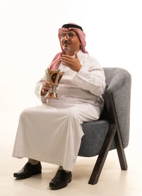 استخدام خشب العود بالأعياد والمناسبات, مفهوم التطيب بالبخور, العادات والتقاليد السعودية, بورتريه لرجل كبير مسن عربي خليجي سعودي يرتدي الثوب التقليدي والشماغ يجلس على كرسي مريح يقوم بالتعطر من المبخرة, الاهتمام بالمظهر الخارجي والأناقة, خلفية بيضاء