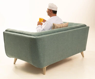Eating light and healthy snacks, entertaining oneself and having a good time, home recreational activities, enjoying popcorn, a large portrait from behind of an elderly Arab Gulf Omani man wearing a traditional dishdasha and kumma holding a box of corn, delicious snacks and crisps, white background.