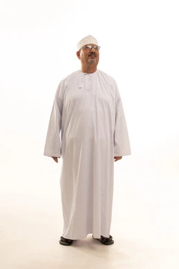 الاهتمام بالمظهر الخارجي، مفهوم الرجولة والوقار، بورتريه لرجل كبير بالسن عربي خليجي عماني يرتدي الدشداشة التقليدية والكمه العمانية والنظارة الطبية يقف بشكل مستقيم وينظر إلى الكاميرا بإيماءات البشاشة والسرور، الجسم بالطول الكامل، خلفية بيضاء