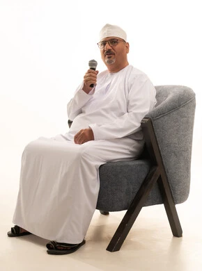 إقامة الندوات وورش العمل والتحاور والنقاش مع الآخرين، تسجيل المقاطع الصوتية والغنائية، تبادل الحوار والاستفادة من خبرات كبار السن، بورتريه لرجل عربي خليجي عماني يرتدي الدشداشة والعمامة يجلس على كرسي مريح يحمل بيده مكبر الصوت، صورة الجسم بالطول الكامل، خلفية بيضاء إقامة الندوات وورش العمل والتحاور والنقاش مع الآخرين، تسجيل المقاطع الصوتية والغنائية، تبادل الحوار والاستفادة من خبرات كبار السن، بورتريه لرجل عربي خليجي عماني يرتدي الدشداشة والعمامة يجلس على كرسي مريح يحمل بيده مكبر الصوت، صورة الجسم بالطول الكامل، خلفية بيضاء