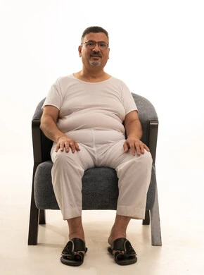 النظر إلى الكاميرا بإيماءات السرور والسعادة، بورتريه لرجل كبير بالسن عربي سعودي خليجي يرتدي سروال و فانيلة ويضع نظارات طبية يجلس على كرسي مريح، خلفية بيضاء النظر إلى الكاميرا بإيماءات السرور والسعادة، بورتريه لرجل كبير بالسن عربي سعودي خليجي يرتدي سروال و فانيلة ويضع نظارات طبية يجلس على كرسي مريح، خلفية بيضاء