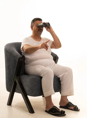 The love of exploration and adventure, pointing with the index finger at something, futuristic visions among adults and the elderly, a portrait of an elderly Arab Saudi Gulf man smiling, wearing pants and a tank top and medical glasses, looking through a binocular telescope, seeing distant objects, white background.