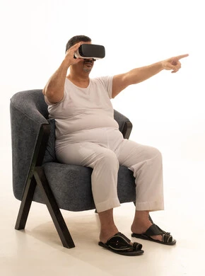Pointing with the index finger at something, interacting and merging with holographic elements, the concept of modern electronic technologies, a portrait of an elderly Arab Saudi Gulf man sitting in a comfortable chair wearing white pants and a tank top and 3D virtual reality (VR) glasses, white background.