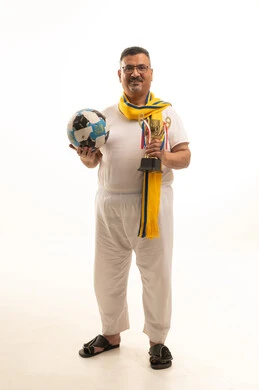 Excitement and interaction with the national team, looking at the camera with gestures of joy for the victory, a portrait of an elderly Arab Gulf Saudi man wearing pants and a shirt and medical glasses, wearing a scarf of his favorite team and holding the golden cup and a football, supporting sports clubs, full-body shot, white background.