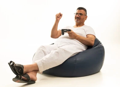Modern entertaining technologies, spending enjoyable and fun time, interaction and immersion with PlayStation games, gestures of victory and triumph, a portrait of an elderly Arab Saudi Gulf man wearing white pants and a t-shirt sitting on a comfortable chair holding a game controller and playing video games, white background.