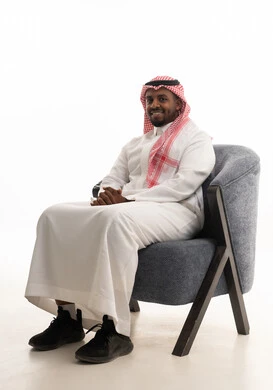 The concept of elegance and self-care, taking care of one's appearance, a portrait of a smiling Saudi Arabian Gulf man wearing a ghutrah and traditional thobe sitting on a comfortable chair looking at the camera, gestures of joy and self-confidence, a personal photo for official documents, white background.