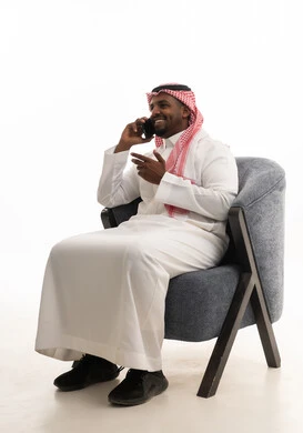 إجراء مكالمة هاتفية مع الأهل والأصدقاء، تصفح مواقع التواصل الاجتماعي ، دمج التقنيات الحديثة فى الحياة اليومية ، استخدام الهاتف المحمول ، بورتريه لرجل عربي خليجي سعودي يرتدي الثوب التقليدي والشماغ يمسك الجوال بيده ، خلفية بيضاء