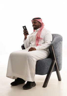 استخدام الهاتف المحمول ، دمج التقنيات الحديثة فى الحياة اليومية ، إجراء مكالمة هاتفية مع الأهل والأصدقاء، تصفح مواقع التواصل الاجتماعي ، بورتريه لرجل عربي خليجي سعودي يرتدي الثوب التقليدي والشماغ يمسك الجوال بيده ، خلفية بيضاء