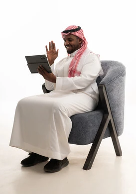 دمج التقنيات الحديثة فى الحياة اليومية ، استخدام الجهاز اللوحي  ، إجراء بث مباشر مع الأهل والأصدقاء، تصفح مواقع التواصل الاجتماعي ، بورتريه لرجل عربي خليجي سعودي يرتدي الثوب التقليدي والشماغ يمسك جهاز التابلت بيده ، خلفية بيضاء