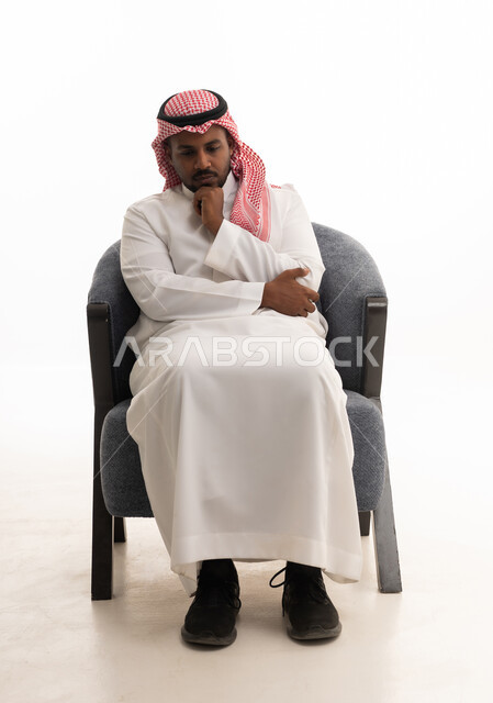 التفكير بعمق وشرود الذهن،القلق والحيرة في اتخاذ القرار الصحيح، محاولة إيجاد حل للمشكلات الصعبة، بورتريه لرجل عربي خليجي سعودي يرتدي الثوب التقليدي والشماغ  يضع يده بإيماءات الحيرة، خلفية بيضاء