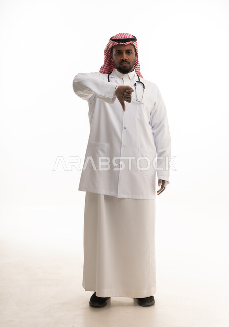 ايماءات الرفض وعدم الموافقة ، العمل في القطاع الصحي السعودي، إجراء الفحوصات اللازمة، مفهوم الطب والرعاية الصحية ، بورتريه لطبيبب سعودي خليجي مبتسم يرتدي الشماغ والزي التقليدي والمعطف الابيض ينظر للكاميرا يقدم خدماته للمرضى بكل كفاءه،  خلفية بيضاء