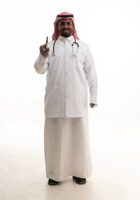 العمل في القطاع الصحي السعودي، اشارات اليد لاعلى ، إجراء الفحوصات اللازمة، مفهوم الطب والرعاية الصحية ، بورتريه لطبيبب سعودي خليجي مبتسم يرتدي الشماغ والزي التقليدي والمعطف الابيض ينظر للكاميرا يقدم خدماته للمرضى بكل كفاءه،  خلفية بيضاء
