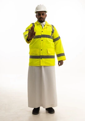 الاشاره بترك مسافة امان ،مهن ووظائف سعودية، مفهوم الهندسة والانشاءات المعمارية، بورتريه لمهندس عربي خليجي سعودي مبتسم يرتدي الثوب التقليدي والخوذه وسترة الحماية ينظر بإيماءات السرور، الوقوف بأيدي متقاطعه، العمل في القطاع الهندسي،الإعمار بسواعد أبناء الوطن