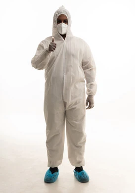 ايماءات الرضي والموافقة ، بورتريه لطبيب سعودي يرتدي معدات وقائية لمكافحة فيروس كورونا يرتدي رداء أبيض بلاستيكي قياسي و كمامة الوجه ينظر الى الكاميرا بتعابير الجدية، تجنب انتشار العدوى ، خلفية بيضاء