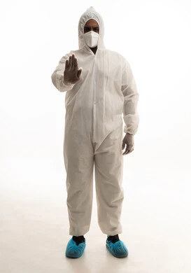 اشارات البعد وعدم التقرب ، بورتريه لطبيب سعودي يرتدي معدات وقائية لمكافحة فيروس كورونا يرتدي رداء أبيض بلاستيكي قياسي و كمامة الوجه ينظر الى الكاميرا بتعابير الجدية، تجنب انتشار العدوى ، خلفية بيضاء