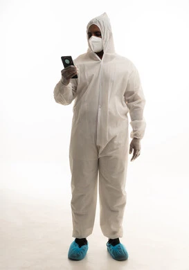 التكنولوجيا والتقنيات الحديثة فى العمل ،بورتريه لطبيب سعودي يرتدي معدات وقائية لمكافحة فيروس كورونا يرتدي رداء أبيض بلاستيكي قياسي و كمامة الوجه ، استخدام الهاتف المحمول ، تجنب انتشار العدوى ، خلفية بيضاء