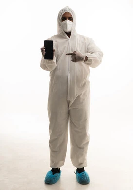 استخدام الهاتف المحمول ،  بورتريه لطبيب سعودي يرتدي معدات وقائية لمكافحة فيروس كورونا يرتدي رداء أبيض بلاستيكي قياسي و كمامة الوجه ، التكنولوجيا والتقنيات الحديثة فى العمل ، عرض شاشة سوداء، تجنب انتشار العدوى ، خلفية بيضاء