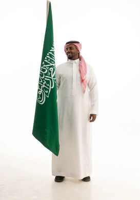 الفخر و الاعتزاز بالانتماء للمملكة, بورتريه لرجل عربي سعودي خليجي مبتسم يرتدي الشماغ والثوب التقليدي يحمل بيده علم السعودية , يوم العلم 11مارس، الاحتفال بذكرى اليوم الوطني السعودي 8 ربيع الأول, خلفية بيضاء