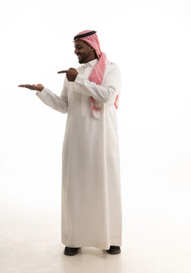 بورتريه لرجل عربي خليجي سعودي مبتسم يرتدي الشماغ والثوب التقليدي يشير بإصبع السبابة ليده الأخرى، الامساك بعنصر ما بإيماءات الاعجاب، تعابير الفرح والسرور والاشاره الى شئ ما، خلفية بيضاء