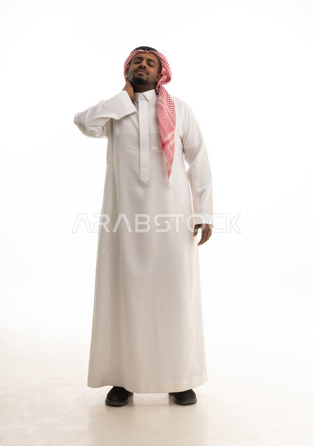 وجع مفاصل و عظام الرقبة, الحاجة للعلاج الفيزيائي، آلام العنق والعمود الفقري,  الإحساس بالتعب والإرهاق, بورتريه لرجل عربي خليجي سعودي مبتسم يرتدي الشماغ والثوب التقليدي يضع يده حول عنقه بإيماءات الألم, الجسم بالطول الكامل, خلفية بيضاء
