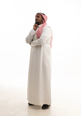 القلق والحيرة في اتخاذ القرار الصحيح، التفكير بعمق وشرود الذهن، محاولة إيجاد حل للمشكلات الصعبة، بورتريه لرجل عربي خليجي سعودي يرتدي الثوب التقليدي والشماغ  يضع يده بإيماءات الحيرة، خلفية بيضاء