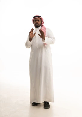 طلب التوقف و الامتناع و عدم الاقتراب, حماية النفس من ضرر خارجي, بورتريه لرجل عربي خليجي سعودي يرتدي الثوب التقليدي والشماغ ينظر إلى الكاميرا و يرفع يديه بتعابير الخوف و الابتعاد, الجسم بالطول الكامل, خلفية بيضاء