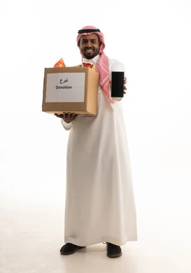 بورتريه لرجل عربي خليجي سعودي يرتدي الشماغ والثوب التقليدي يحمل بيده صندوق مواد التنظيف ينظر الى الكاميرا بإيماءات السرور، التبرع لمشروع نظافة المسجد في الجمعية الاسلامية في المملكة، عرض شاشة سوداء عبر الجوال ، فعالية تطوعية واعمال خيرية، مبادرة وتبرع انساني خيري،خلفية بيضاء