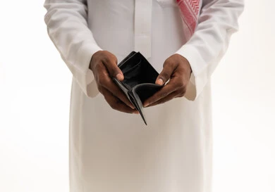 ايماءات الفقر والحاجه للمال والمساعدة ، تعابير الحزن والاكتئاب، مفهوم الافلاس وعدم امتلاك الأموال، بورتريه مقرب ليد رجل عربي خليجي سعودي يرتدي الثوب التقليدي والشماغ  يفتح بيده محفظة جيب جلدية فارغه , خلفية بيضاء