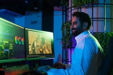 صورة لمونتير عربي خليجي سعودي يعمل في غرفة المونتاج يستخدم الحاسب المحمول لقص وترتيب المشاهد، استخدام لوحة المفاتيح لتعديل الفيديوهات،مفهوم صناعة المحتوى المرئي والإبداع الفني