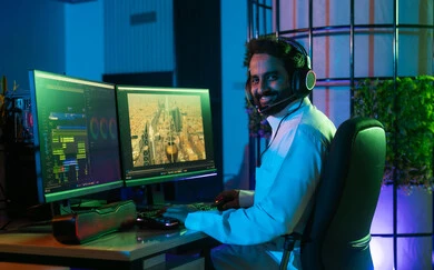 النظر الي الكاميرا بايماءات السعادة ، استخدام برامج المونتاج المتقدمة، صورة من الجانب لمونتير عربي خليجي سعودي يرتدي الثوب الابيض يضع سماعة الراس يعمل في غرفة المونتاج يستخدم الحاسب المحمول لقص وترتيب المشاهد، مفهوم صناعة المحتوى المرئي والإبداع الفني