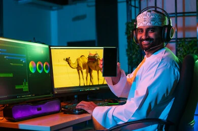 A blank black screen is displayed, the concept of digital content creation, a side image of an Arab Gulf Omani editor wearing a dishdasha and kumma with headphones sitting inside the studio working on arranging scenes using advanced computer and mobile programs, gestures of thinking and concentration.